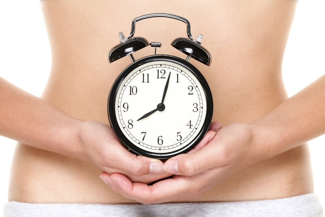 Picture of woman holding a clock over abdomen