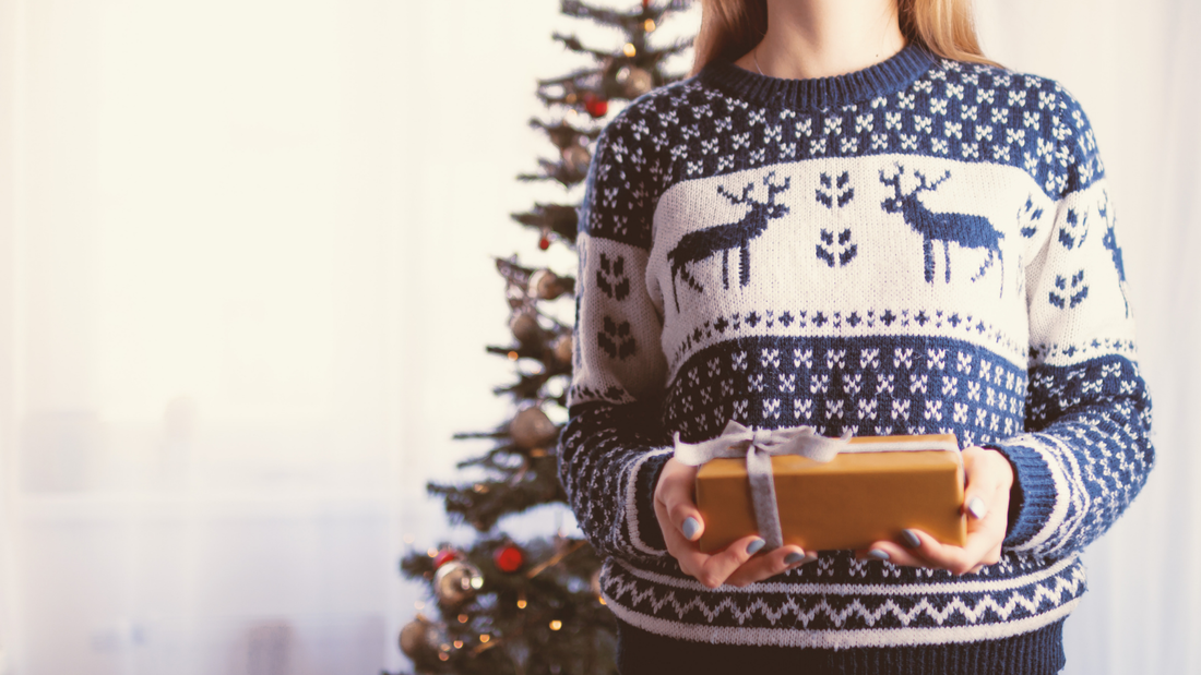 Picture of woman in reindeer jumper holding Christmas gift
