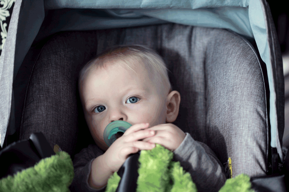 Picture of baby in car seat with pacifier and blanket